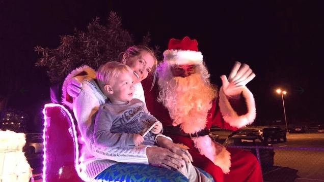 Santa and woman and child in sleigh, waving and smiling