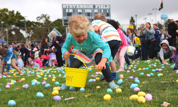 Little girl bending over to pick up eggs in the grass