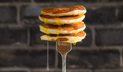 Pancakes dripping with syrup on a fork